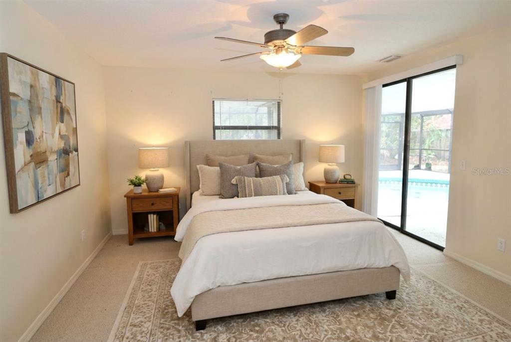 A bedroom features a bed with a beige headboard, two nightstands, and a sliding glass door — 6514 N BISCAYNE DRIVE, NORTH PORT, FL