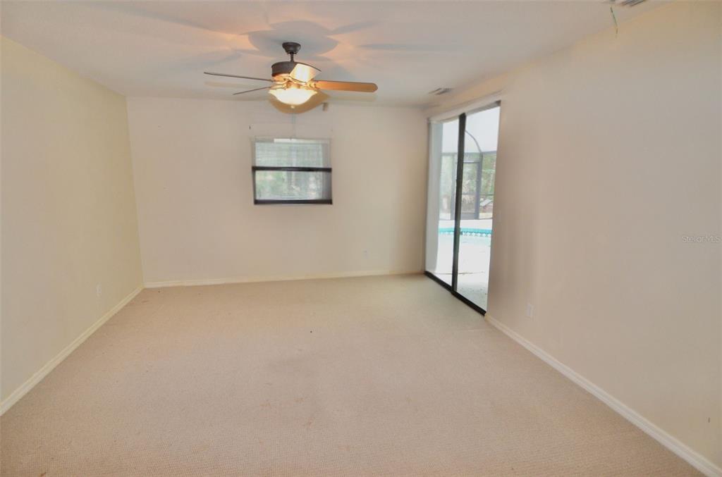 A carpeted room features a ceiling fan, a window with blinds, and sliding glass doors — 6514 N BISCAYNE DRIVE, NORTH PORT, FL