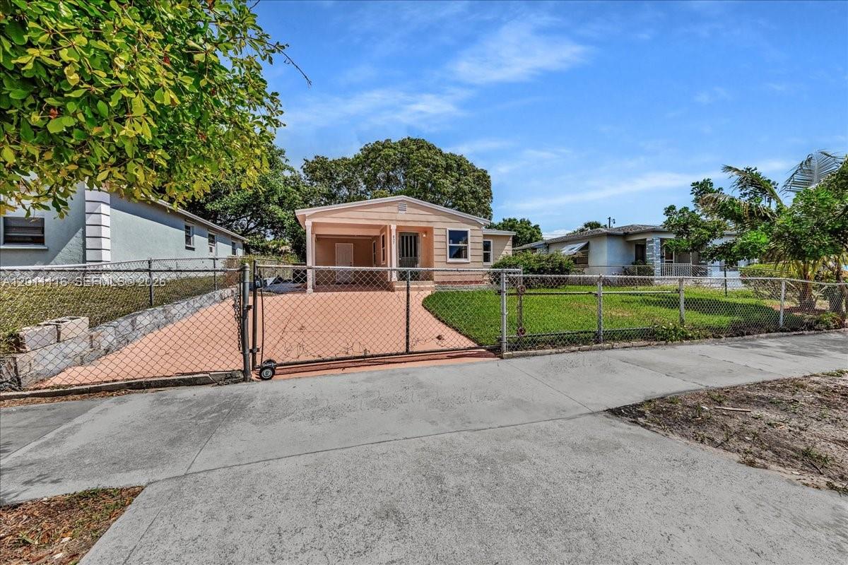 A single-story house with a covered porch and a chain-link fence in the front yard — 837 30th St, West Palm Beach FL 33407, WEST PALM BEACH, FL