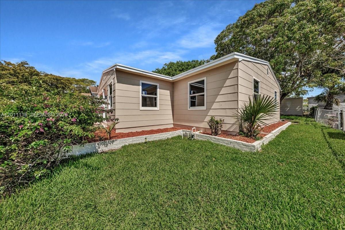 A beige single-story house with horizontal siding stands on a green lawn — 837 30th St, West Palm Beach FL 33407, WEST PALM BEACH, FL
