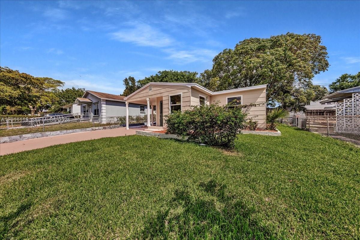 A single-story house with a beige exterior, a front porch, and a large grassy yard — 837 30th St, West Palm Beach FL 33407, WEST PALM BEACH, FL
