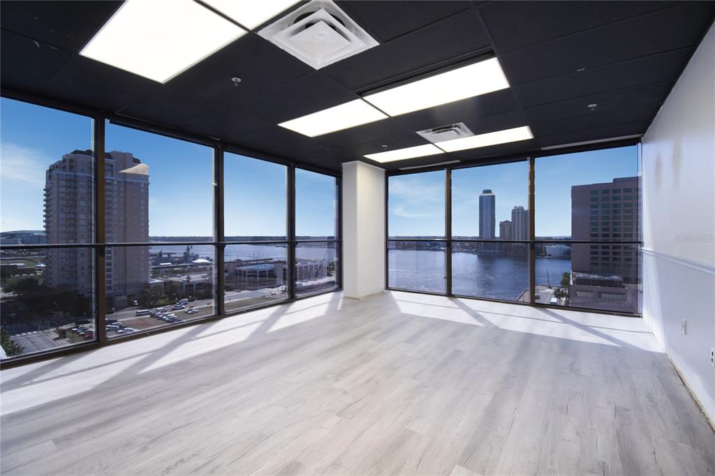 An empty office space features floor-to-ceiling windows with water views and light wood flooring — 233 E BAY STREET UNIT 1101, JACKSONVILLE, FL