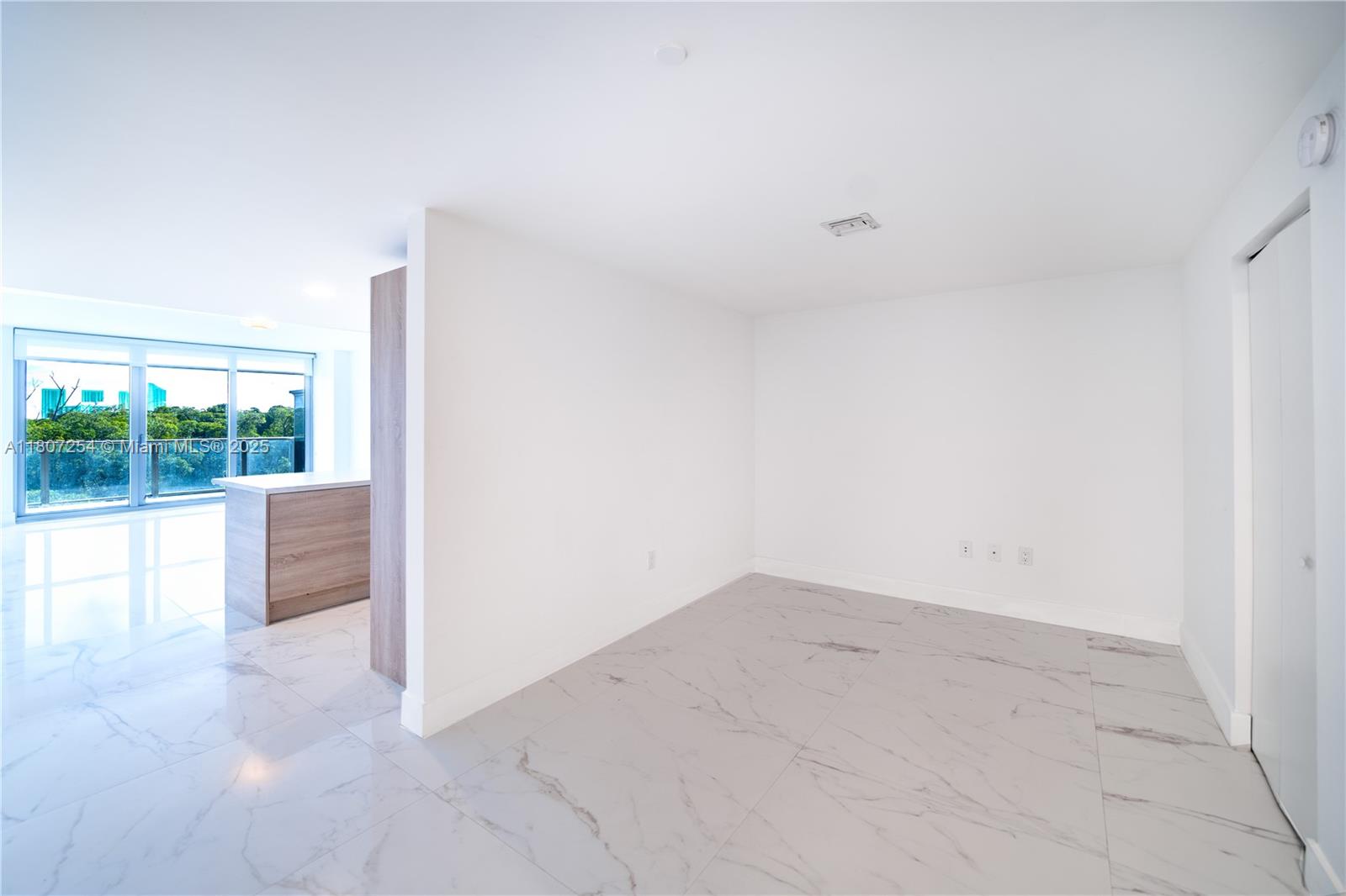 An empty room with white walls, marble-patterned tile floors, and a view of trees outside — 16385 Biscayne Blvd # 417, North Miami Beach FL 33160, NORTH MIAMI BEACH, FL