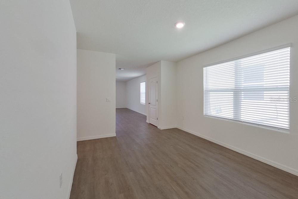 An empty room with light-colored walls, wood-look flooring, and a window with white blinds — 31942 KATELIN CIRCLE, LEESBURG, FL