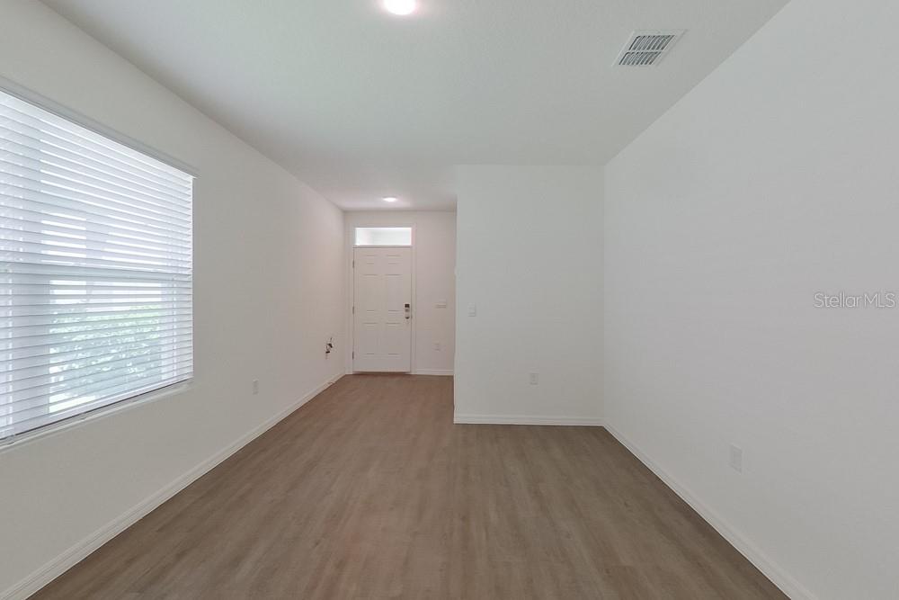 An empty room with white walls, wood-look flooring, and a window with blinds — 31942 KATELIN CIRCLE, LEESBURG, FL