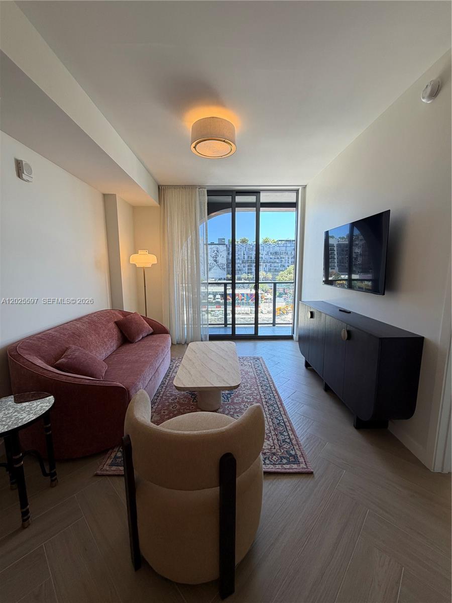 A living room features a pink sofa, a beige armchair, and a wall-mounted television — 2700 NW 2nd ave # 416, Miami FL 33127, MIAMI, FL