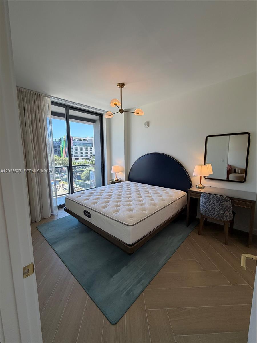 A bedroom features a dark arched headboard, a blue area rug, and a balcony view — 2700 NW 2nd ave # 416, Miami FL 33127, MIAMI, FL