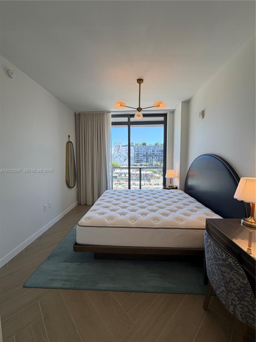 A bedroom features a bed with a dark headboard, a blue rug, and a balcony view — 2700 NW 2nd ave # 416, Miami FL 33127, MIAMI, FL