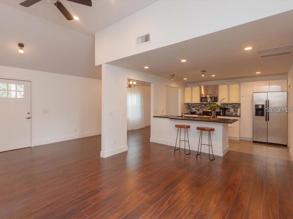 An open-concept kitchen with a breakfast bar overlooks a living area with wood flooring — 1830 STAUNTON AVENUE, WINTER PARK, FL
