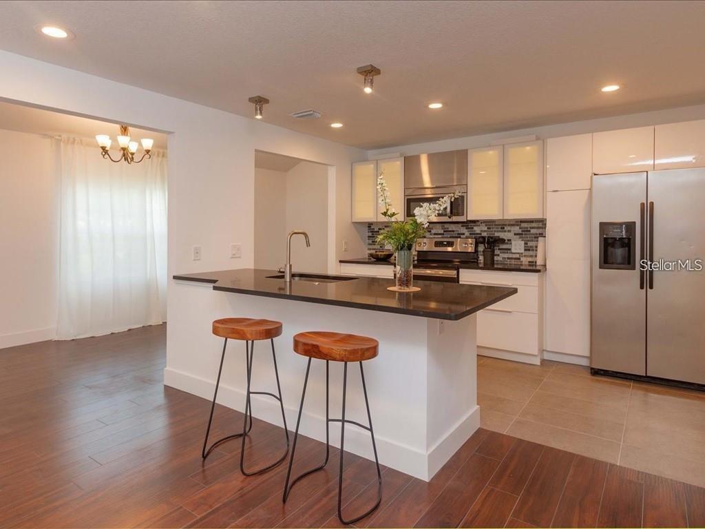 A modern kitchen features a dark countertop island with two wooden bar stools — 1830 STAUNTON AVENUE, WINTER PARK, FL