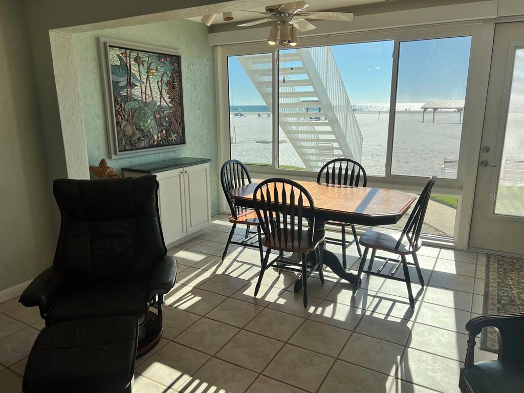 A dining area with a table and chairs overlooks a beach through large glass doors — 6006 MIDNIGHT PASS ROAD UNIT 40, SARASOTA, FL