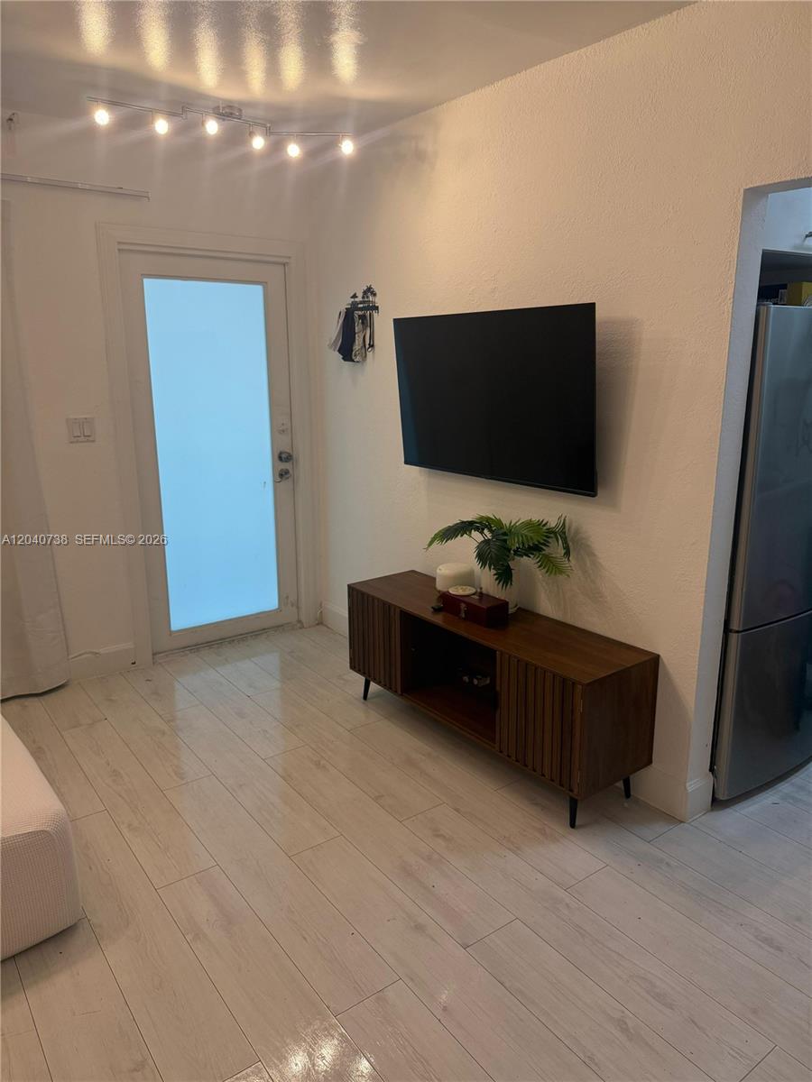A living area features a wall-mounted television above a wooden media console and light-colored flooring — 344 Meridian Ave # 2B, Miami Beach FL 33139, MIAMI BEACH, FL