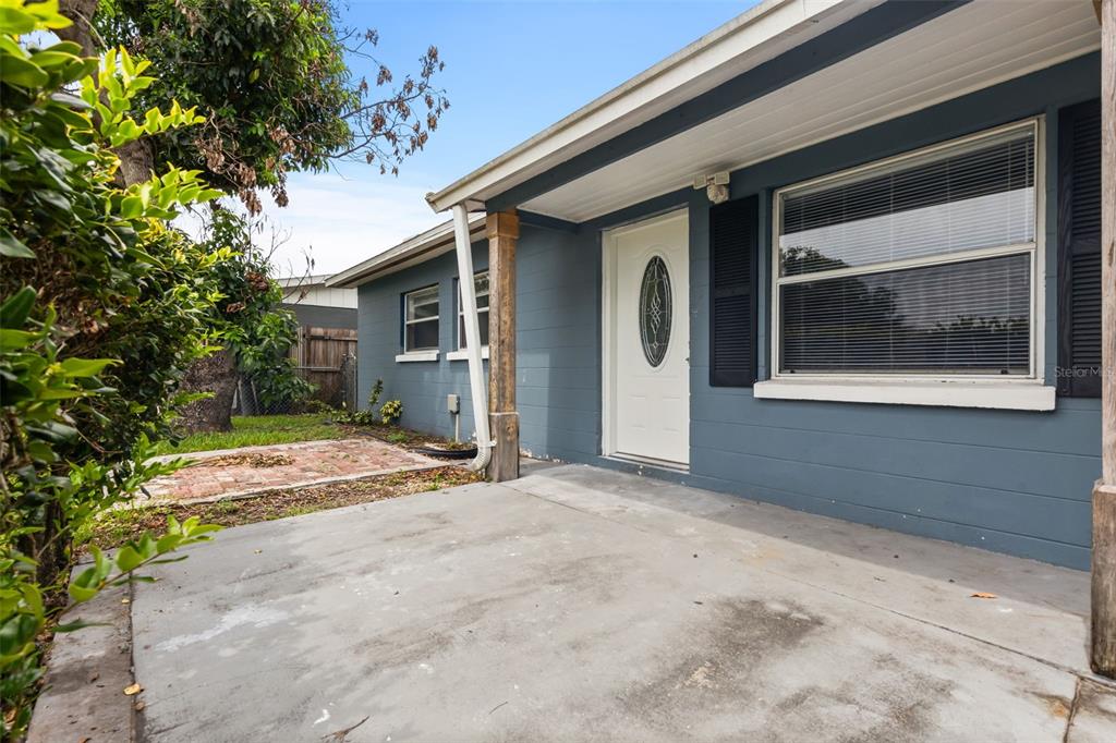 A blue house exterior features a white front door, a concrete porch, and a window — 1039 WOODLAND AVENUE, LAKELAND, FL