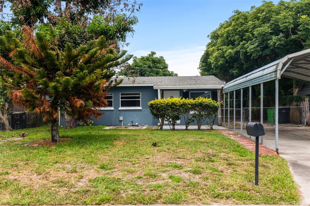 A blue single-story house features a front lawn, a carport, and a mailbox — 1039 WOODLAND AVENUE, LAKELAND, FL