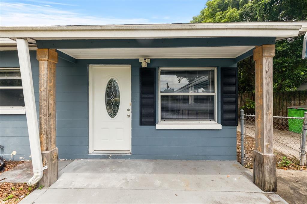 A blue house exterior features a white front door, a window with shutters, and porch columns — 1039 WOODLAND AVENUE, LAKELAND, FL