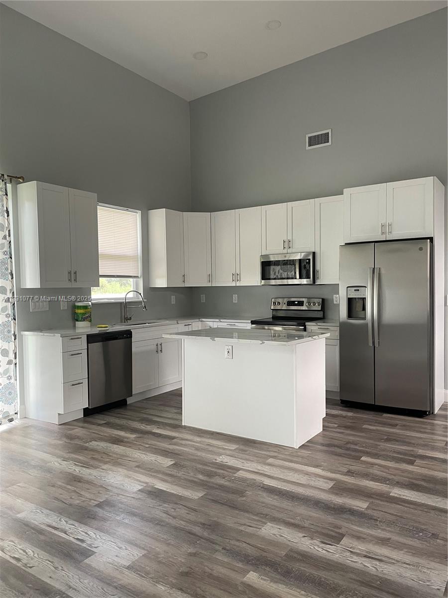 A kitchen features white cabinets, stainless steel appliances, a center island, and wood-look flooring — 2550 N ArrowHead RD # 2550, Avon Park FL 33825, AVON PARK, FL
