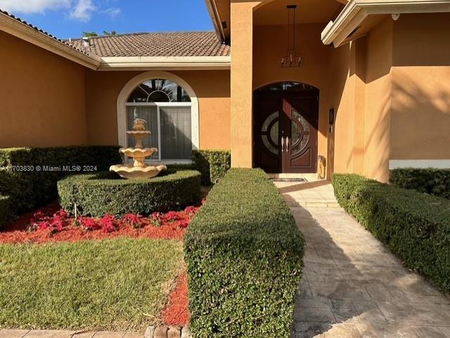 The exterior of a house features a stone fountain, manicured hedges, and a double door — 10601 SW 128th St, Miami FL 33176, MIAMI, FL