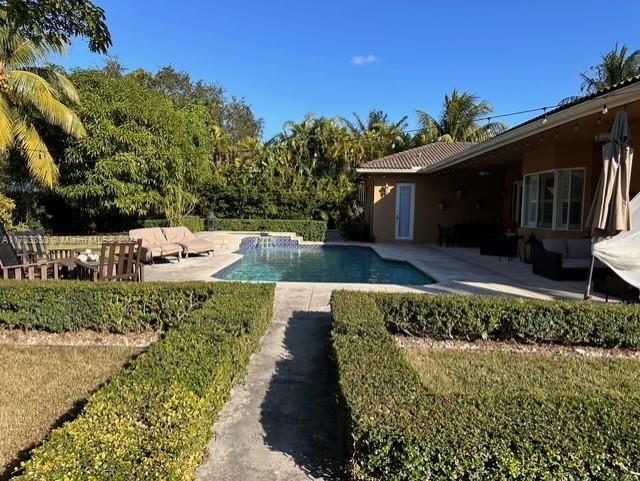 A backyard features a swimming pool, a patio with lounge chairs, and a tan house — 10601 SW 128th St, Miami FL 33176, MIAMI, FL