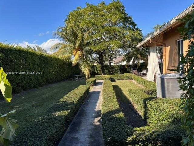 A paved walkway runs through a manicured lawn bordered by hedges next to a house — 10601 SW 128th St, Miami FL 33176, MIAMI, FL