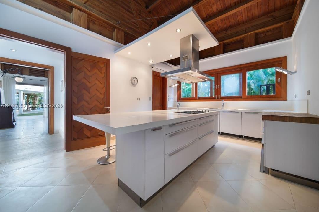 A modern kitchen features a large white island, stainless steel range hood, and wood-paneled ceiling — 0 Las palmas, FL, FL