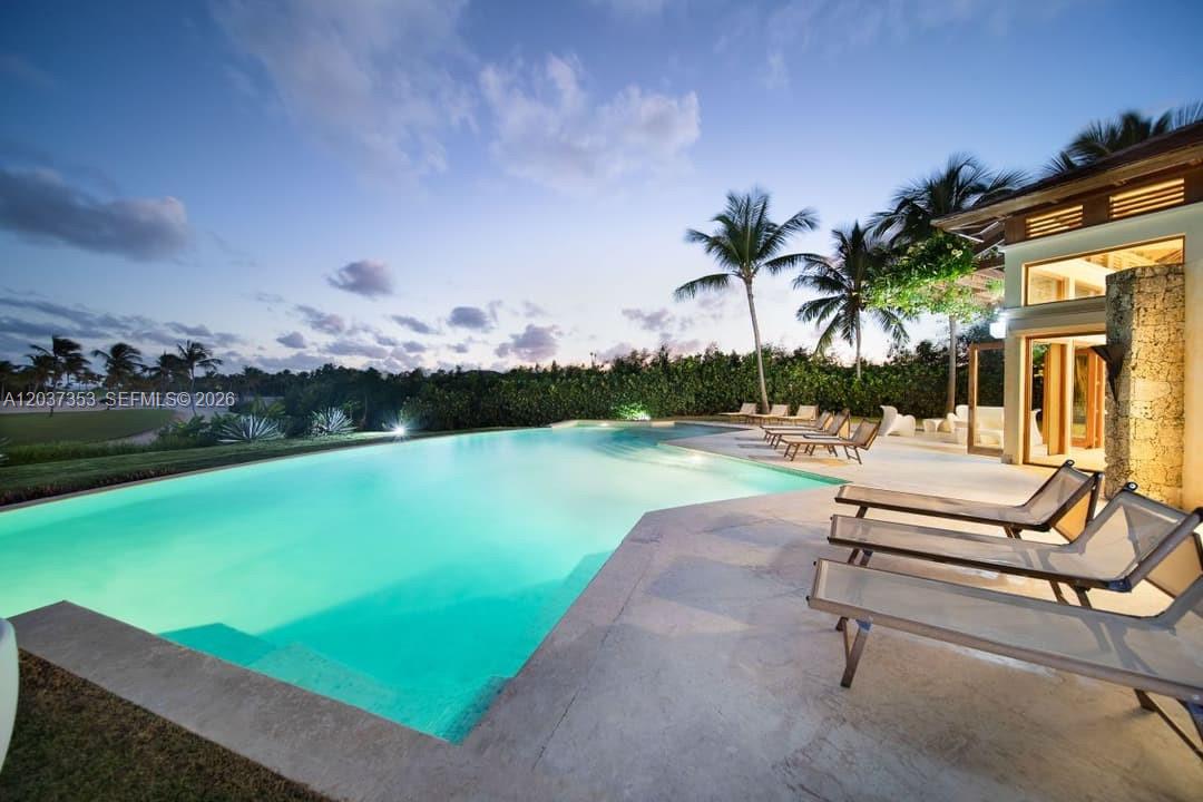 An outdoor swimming pool with lounge chairs on a patio at sunset — 0 Las palmas, FL, FL