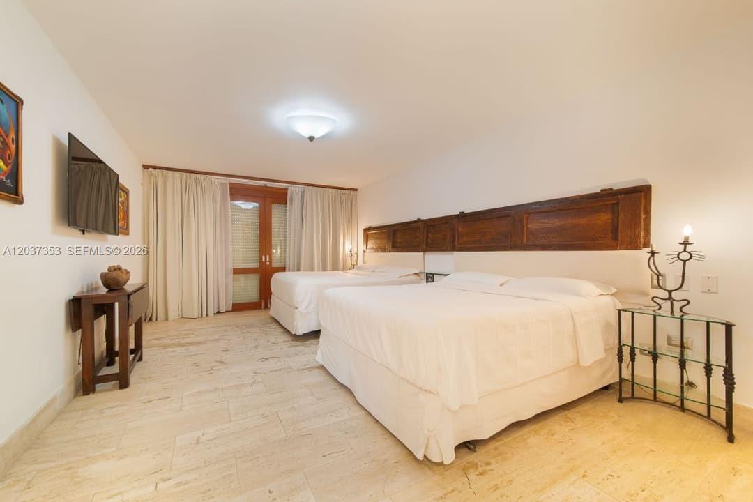 A bedroom features two beds, a wooden headboard, tile floors, and a glass-topped side table — 0 Las palmas, FL, FL