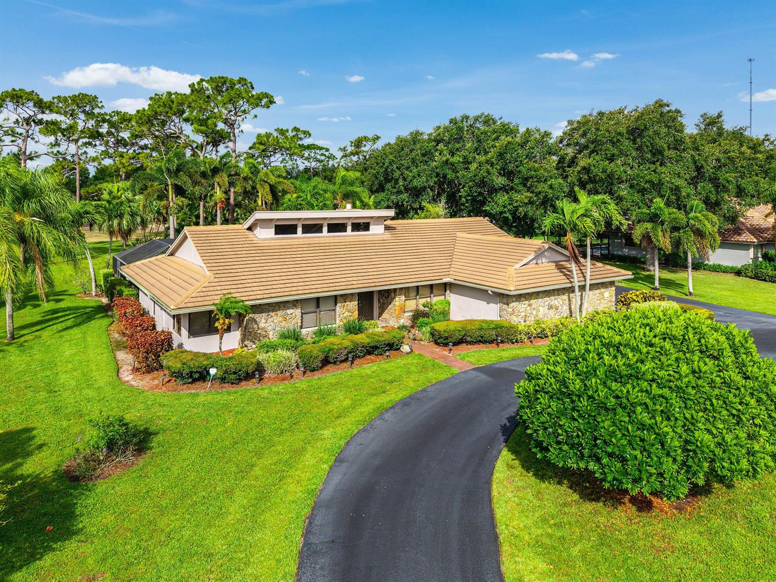 An aerial view of a single-story house with a stone facade and brown tile roof — 9405 Dundee Drive, Lake Worth FL 33467, LAKE WORTH, FL