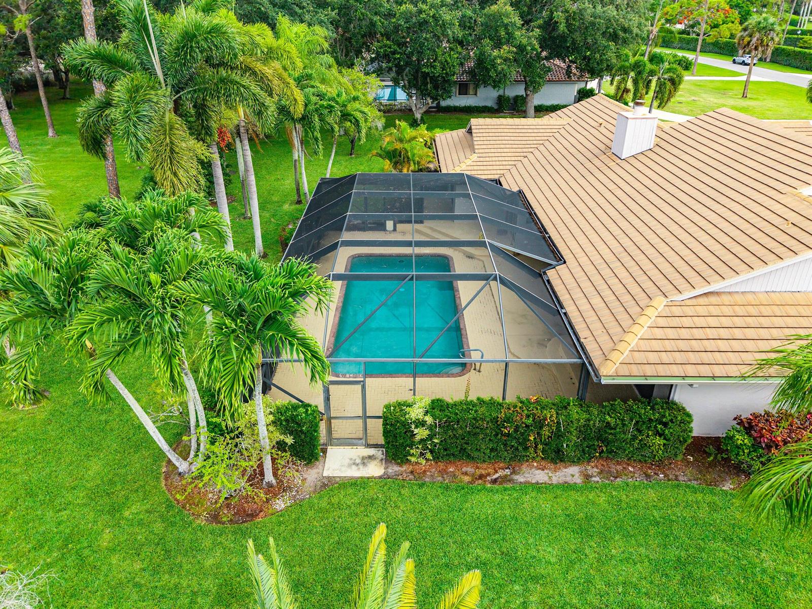 An aerial view of a house with a screened-in swimming pool and surrounding palm trees — 9405 Dundee Drive, Lake Worth FL 33467, LAKE WORTH, FL