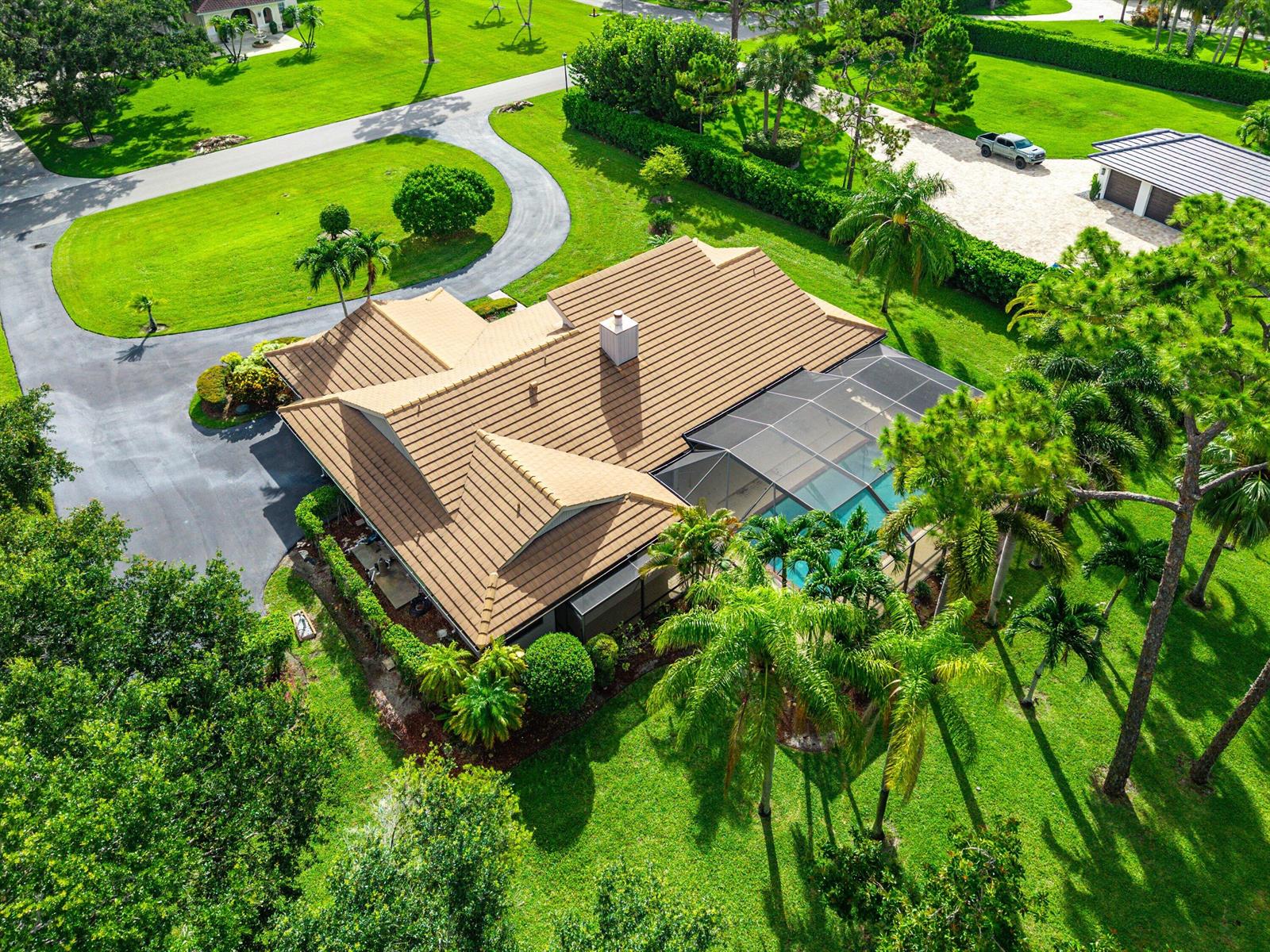 An aerial view of a house with a brown tile roof, pool cage, and driveway — 9405 Dundee Drive, Lake Worth FL 33467, LAKE WORTH, FL