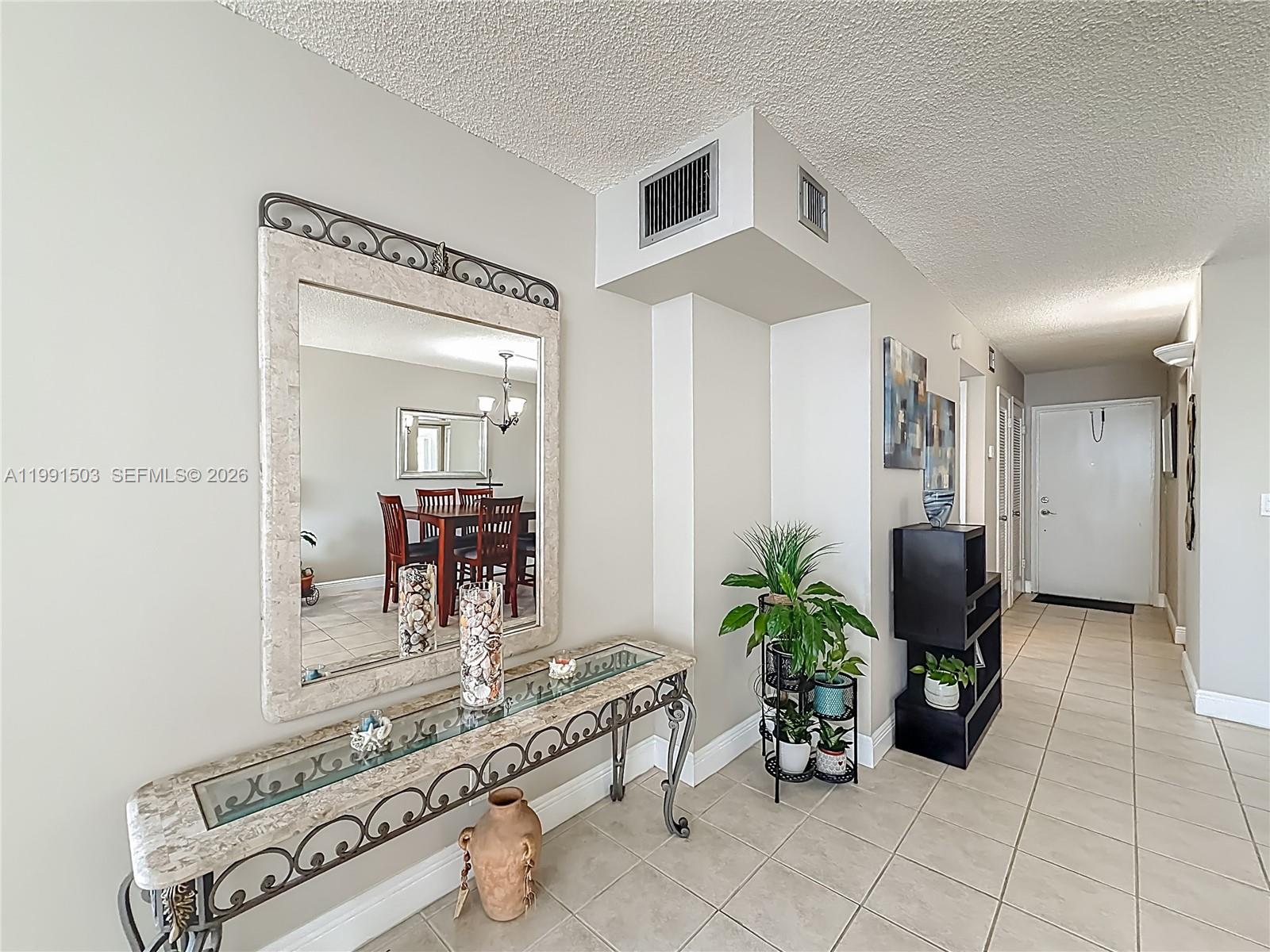 An entryway features a decorative console table, a large mirror, and a plant stand — 400 SE 10th St # 218, Deerfield Beach FL 33441, DEERFIELD BEACH, FL