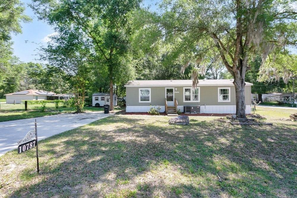A single-story manufactured home with light green siding sits on a grassy lot — 10787 SW 112TH AVENUE, DUNNELLON, FL