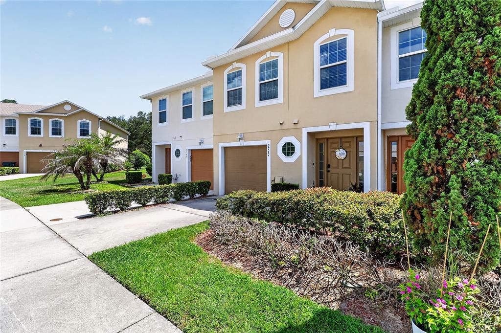 A tan two-story townhouse with a garage, front door, and landscaped yard — 3747 WOODBURY HILL LOOP, LAKELAND, FL