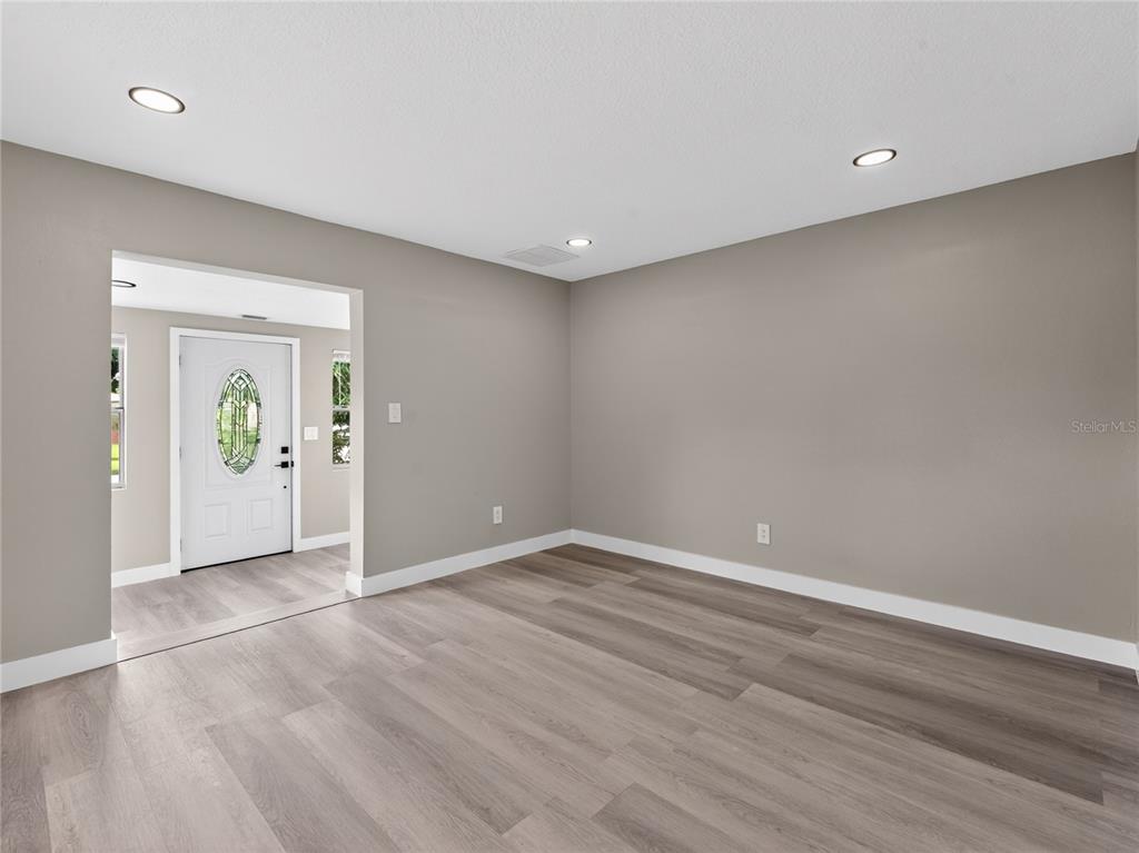 A room with light gray walls, wood-look flooring, recessed lighting, and a white front door — 1900 25TH STREET S, ST PETERSBURG, FL