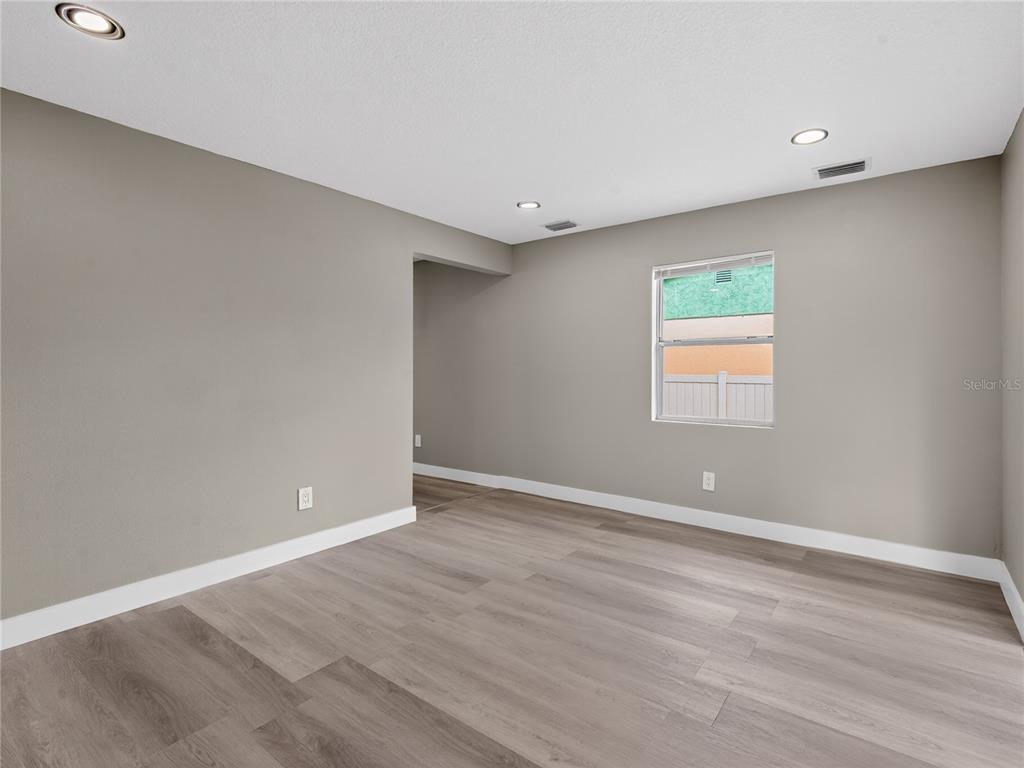 An empty room features gray walls, light wood-look flooring, recessed lighting, and a single window — 1900 25TH STREET S, ST PETERSBURG, FL