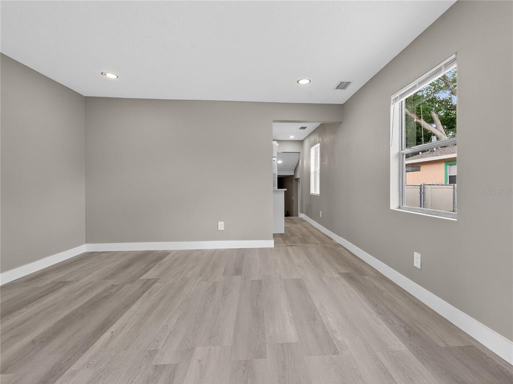 An empty room with gray walls, light wood-look flooring, and a window overlooking a yard — 1900 25TH STREET S, ST PETERSBURG, FL
