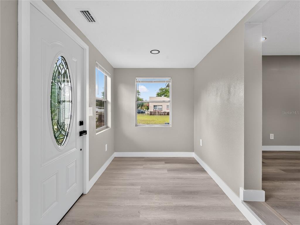 An entryway features light gray walls, wood-look flooring, a white front door, and two windows — 1900 25TH STREET S, ST PETERSBURG, FL