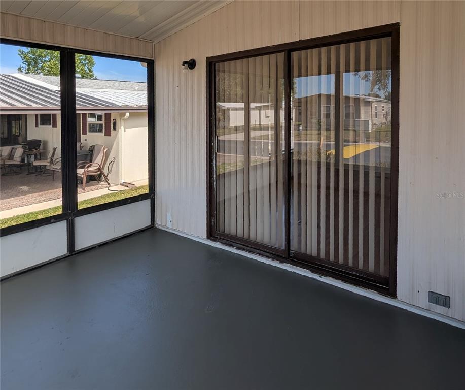 A screened-in porch features gray painted flooring, vertical wall paneling, and a sliding glass door — 34351 TIMBERLAND BOULEVARD, WESLEY CHAPEL, FL