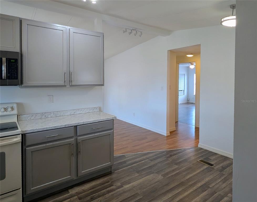 A kitchen with gray cabinets and white countertops opens into a room with wood flooring — 34351 TIMBERLAND BOULEVARD, WESLEY CHAPEL, FL