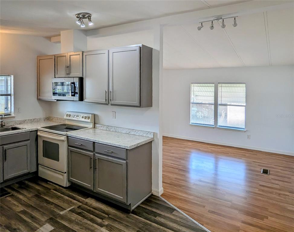 A kitchen with gray cabinets and white countertops opens into a living area with flooring — 34351 TIMBERLAND BOULEVARD, WESLEY CHAPEL, FL