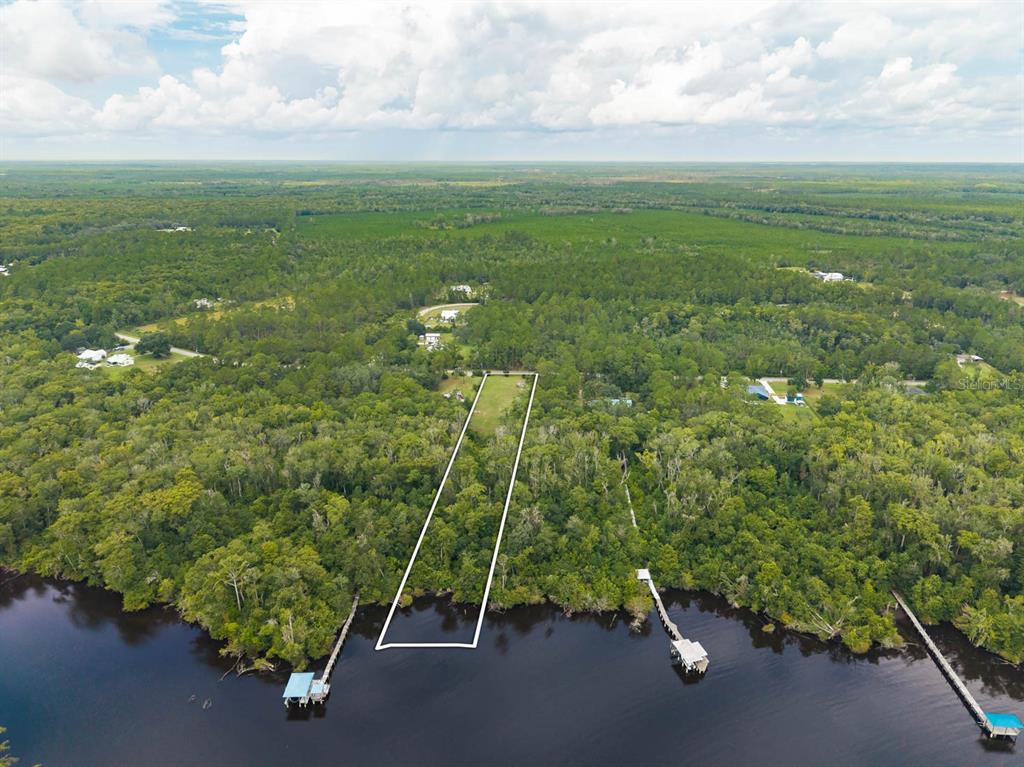 An aerial view shows a narrow, wooded waterfront lot outlined in white along a river — 150 PIONEER TRAIL, GREEN COVE SPRINGS, FL