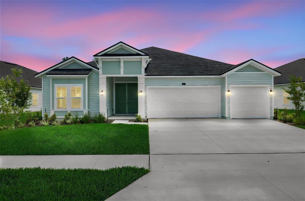 A light green single-story house with a three-car garage and a dark shingled roof — 27 WINDMILL PALM WAY, PALM COAST, FL