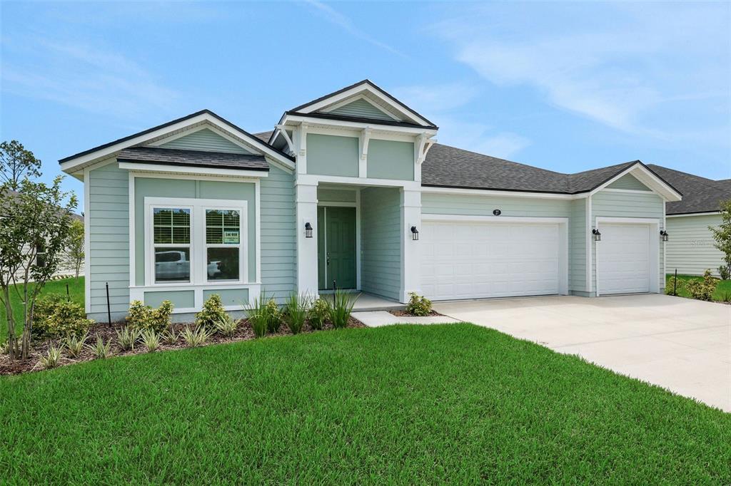 A light green single-story house features a white garage, a covered entryway, and a lawn — 27 WINDMILL PALM WAY, PALM COAST, FL