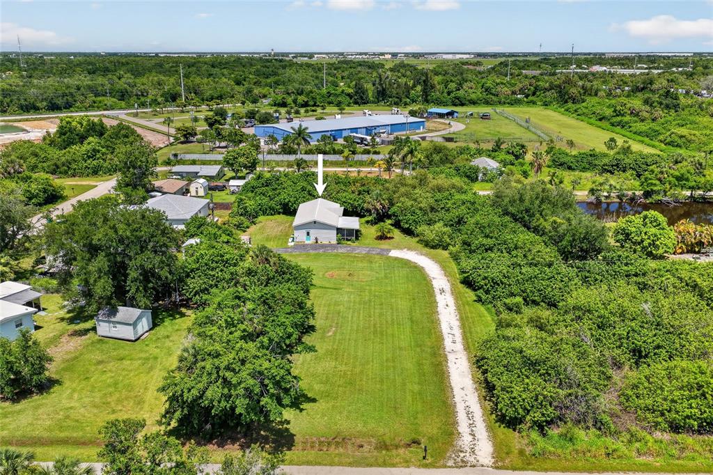 An aerial view shows a single-story house with a long driveway on a grassy lot — 1411 CORAL RIDGE DRIVE, PUNTA GORDA, FL