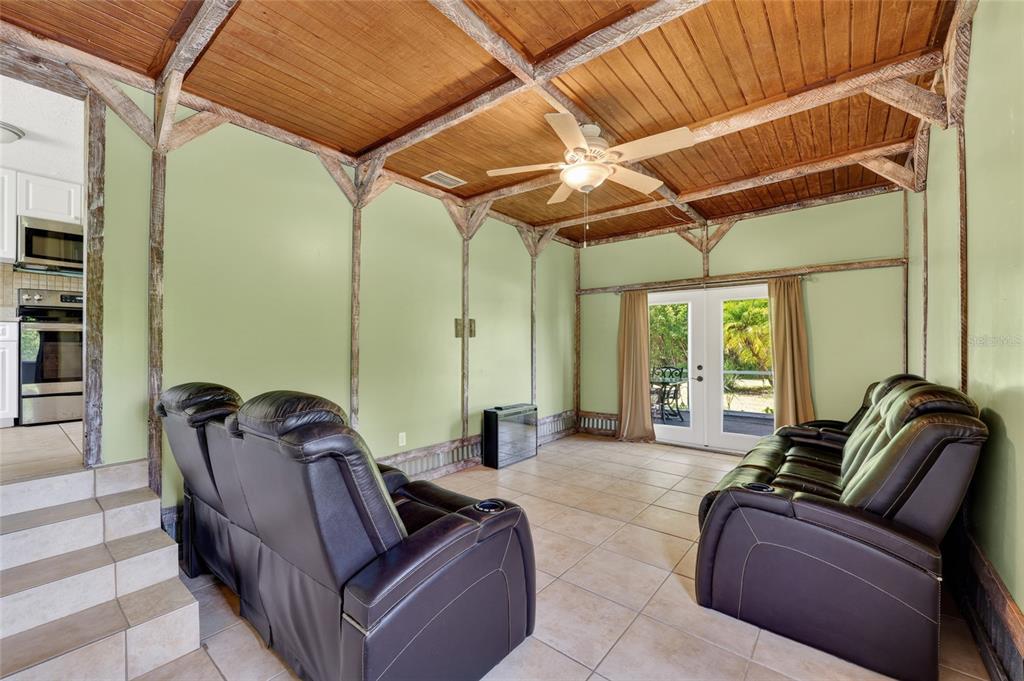 A living room with light green walls, a wood-paneled ceiling, and two leather reclining sofas — 1411 CORAL RIDGE DRIVE, PUNTA GORDA, FL