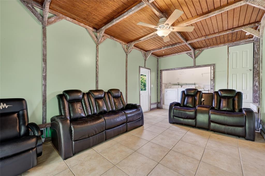 A living room with light green walls, a wood-paneled ceiling, and tiled flooring — 1411 CORAL RIDGE DRIVE, PUNTA GORDA, FL