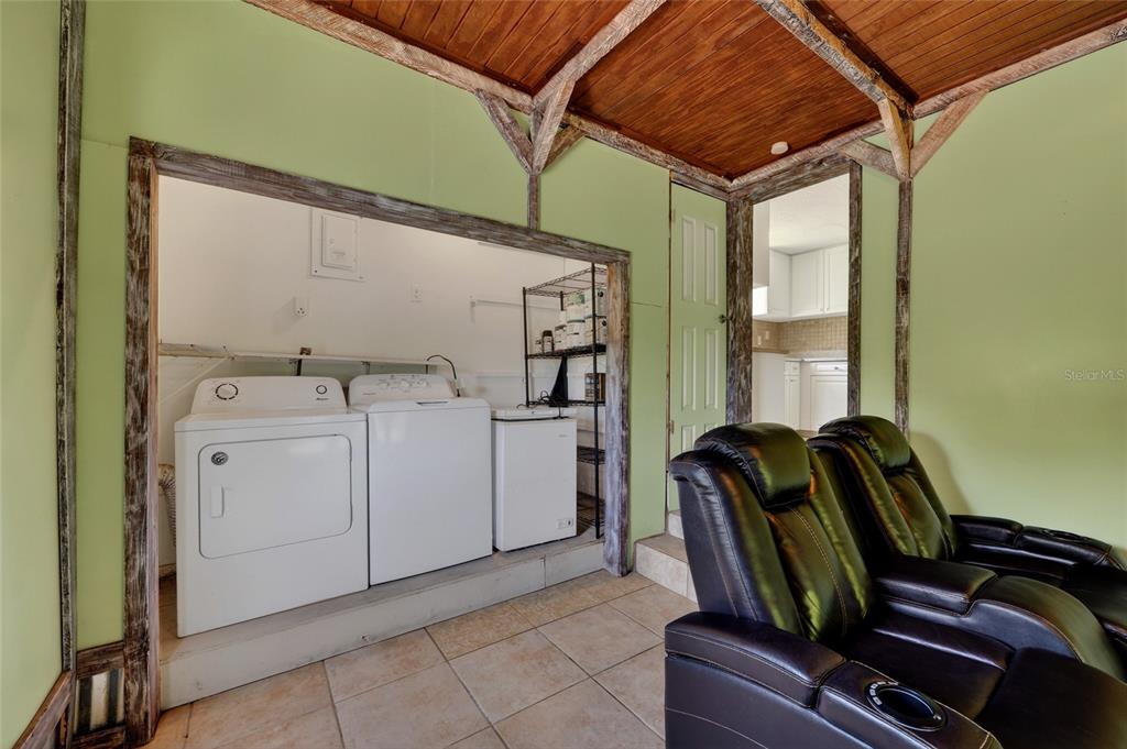 A room with light green walls, a wood-paneled ceiling, tile floors, and laundry appliances — 1411 CORAL RIDGE DRIVE, PUNTA GORDA, FL