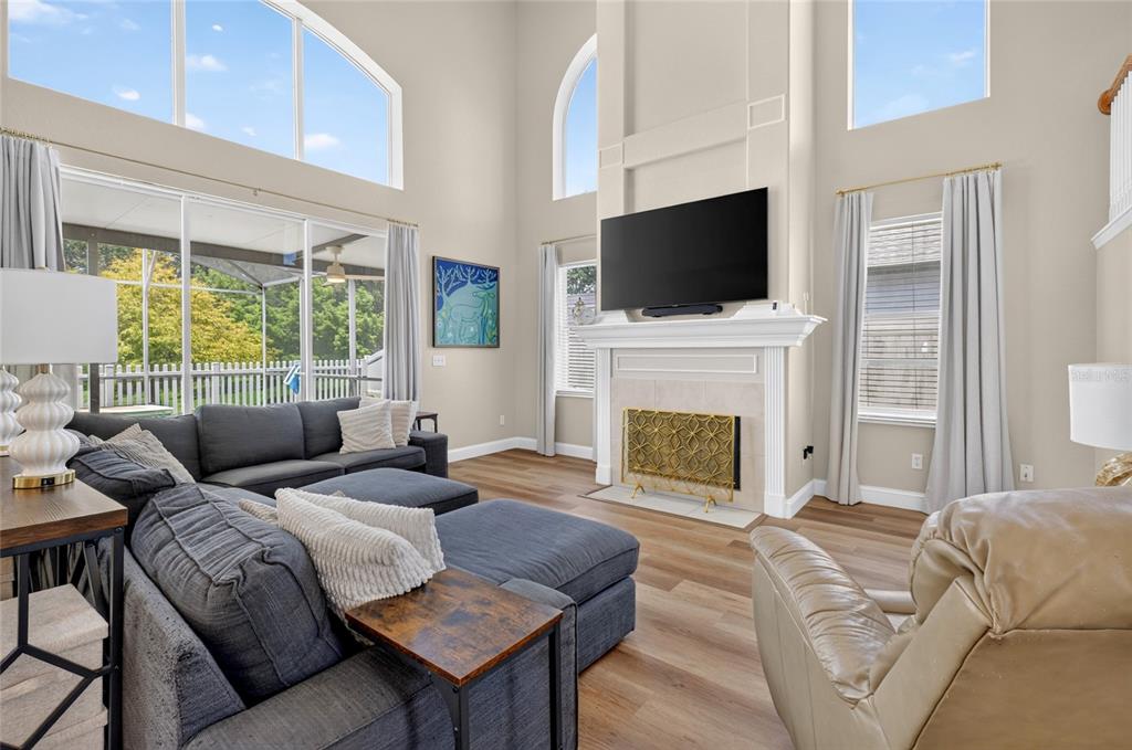 A living room with a high ceiling, fireplace, sectional sofa, and large windows — 353 LAKE AMBERLEIGH DRIVE, WINTER GARDEN, FL