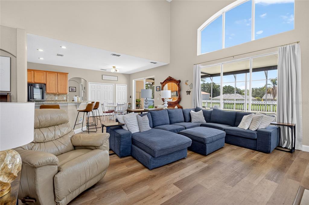 A living room with a large blue sectional sofa, a tan recliner, and an open kitchen — 353 LAKE AMBERLEIGH DRIVE, WINTER GARDEN, FL