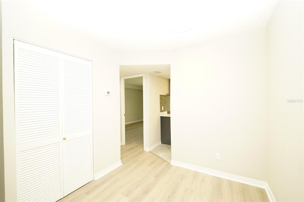 A room with light wood-look flooring, white walls, a louvered closet, and a doorway — 4705 1ST STREET NE UNIT 132, ST PETERSBURG, FL