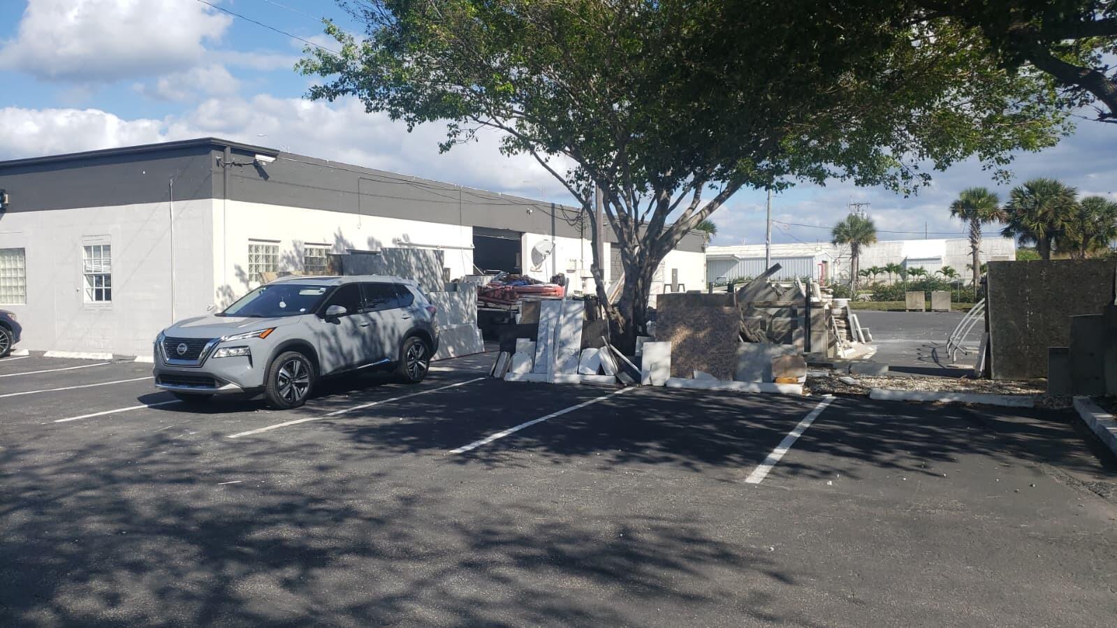A gray SUV is parked in a paved lot next to a building and debris — 1815 10th Avenue N # C, FL 33461, FL
